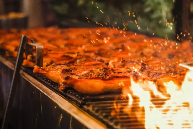 Chicken grilling over open flames, sparks rising