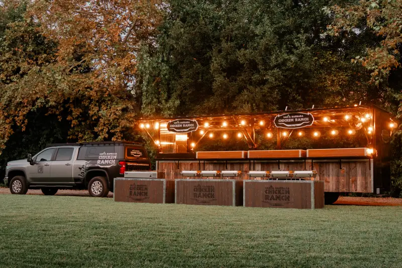 The grill trailer straight on at dusk with the Chicken Ranch truck parked beside it